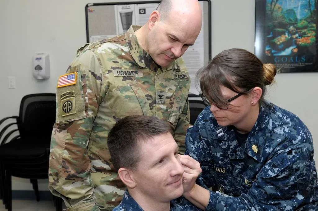 female soldier learning from another soldier how to apply bfa
