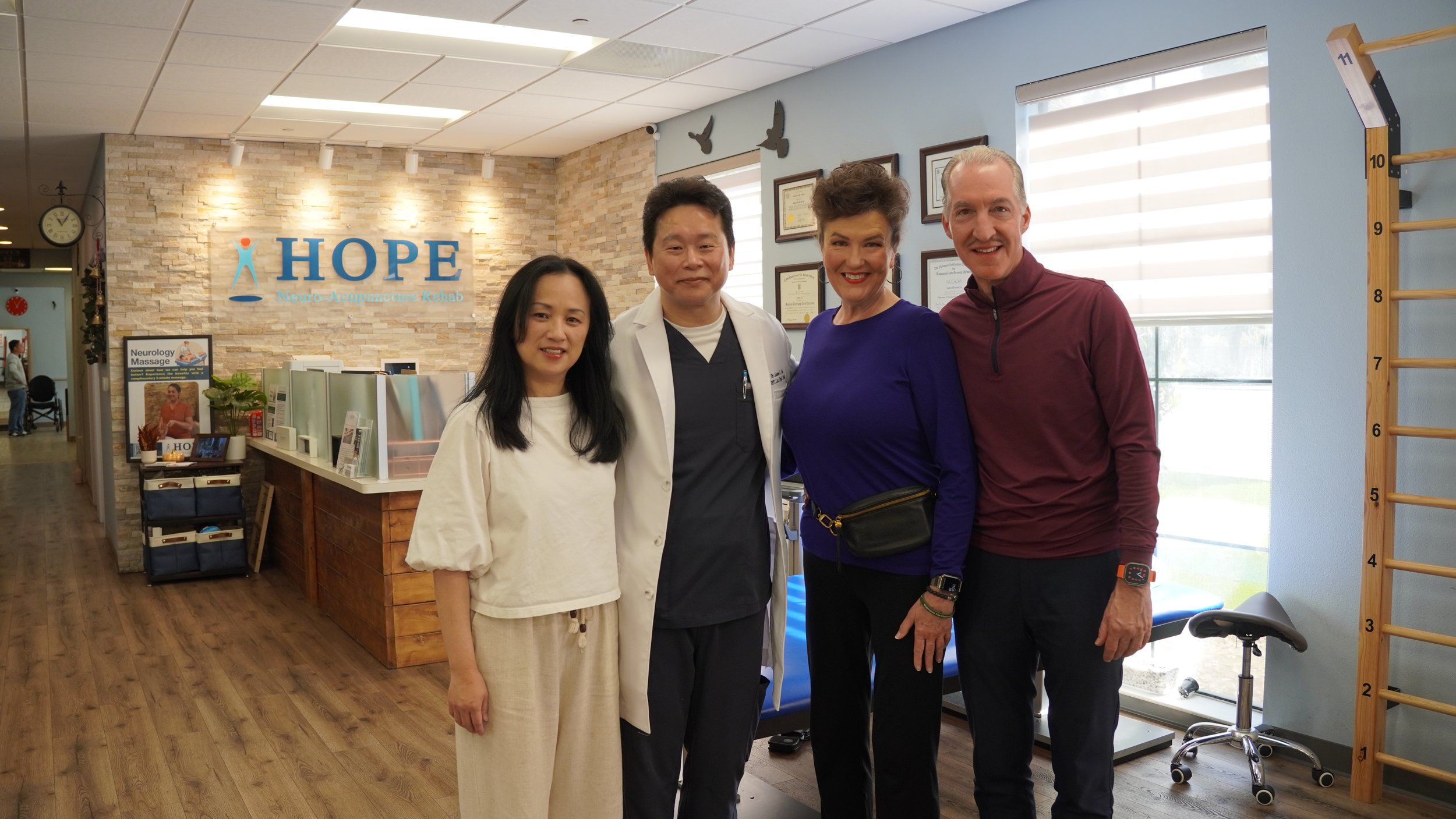 Dr. Lu and staff posing with patient visitors in clinic near HOPE sign