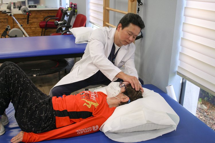 Dr. Lu performing acupuncture on patient lying on treatment table in rehab room