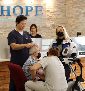 Dr. Lu performing scalp acupuncture on patient at front desk area