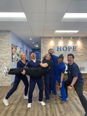 HOPE Clinic staff playfully lifting colleague in lobby for fun group photo